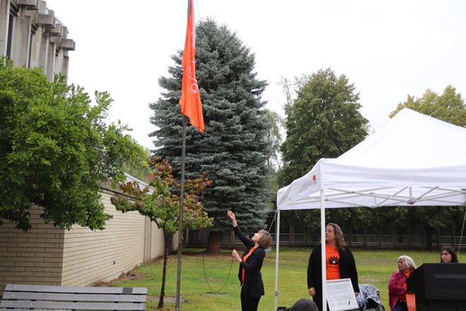 President Maggie Matear raises the Every Child Matters Flag