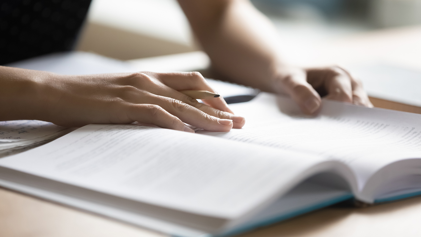 A student looks at a book while taking an exam