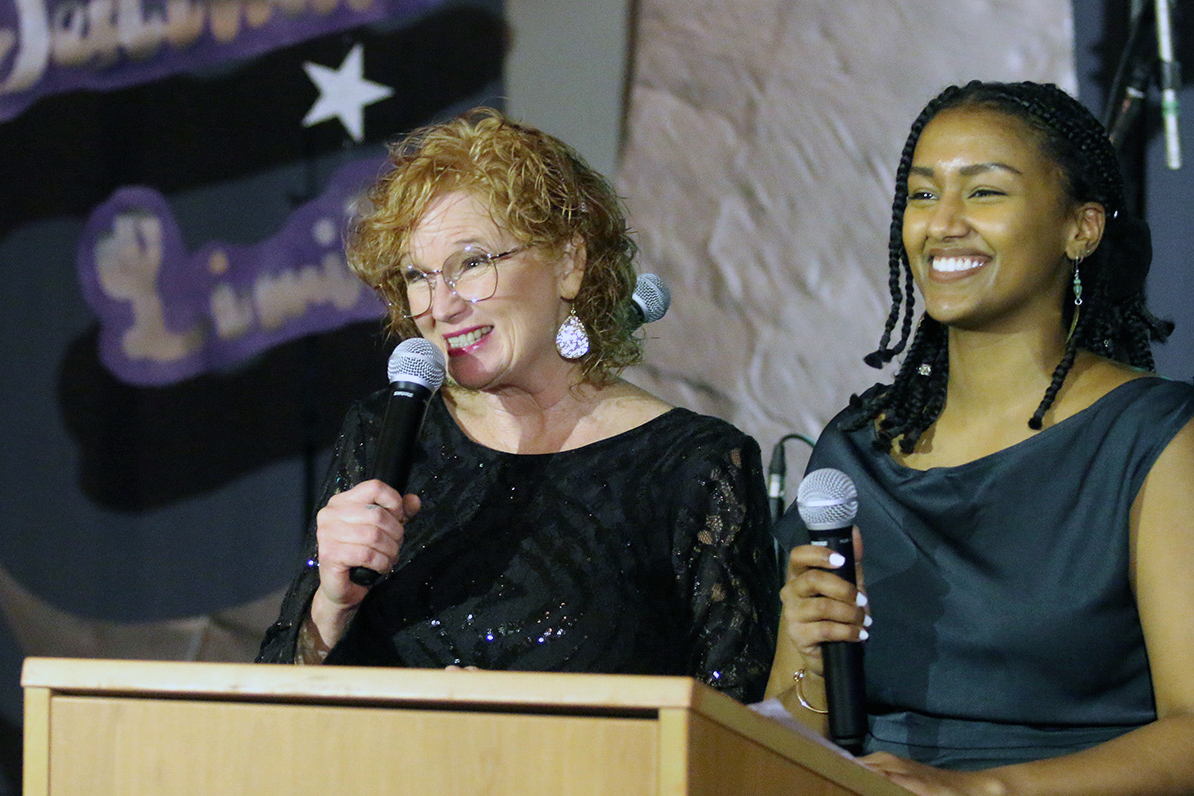 Two people stand at podium and MC Gala