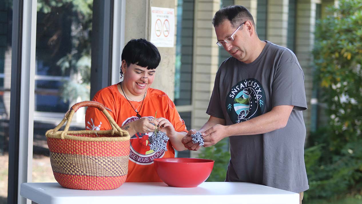 Two people pick and clean berries