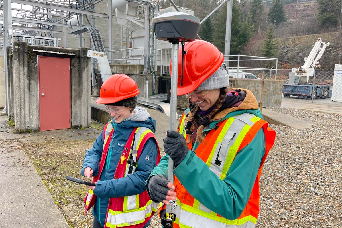Two student interns stand outside holding equipment