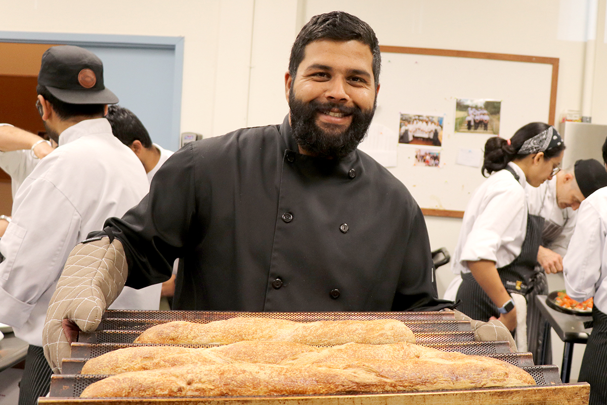 Professional Cook student holding a fresh pan of bread