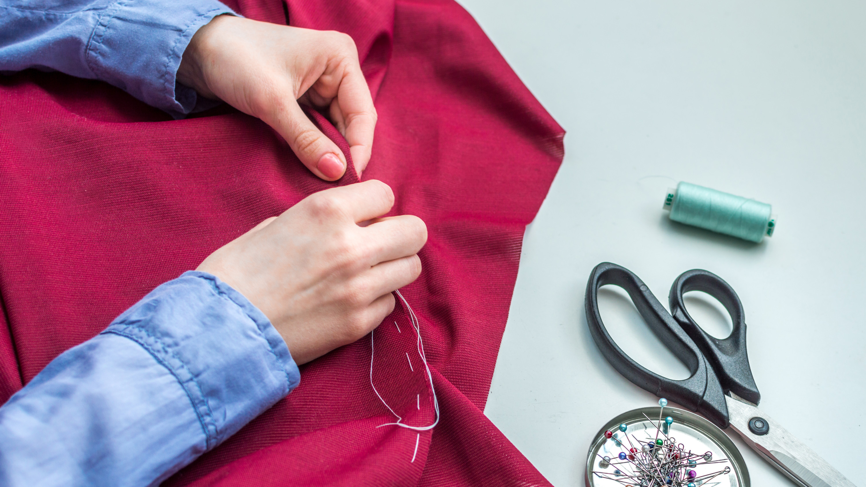 Hands sewing a piece of red fabric