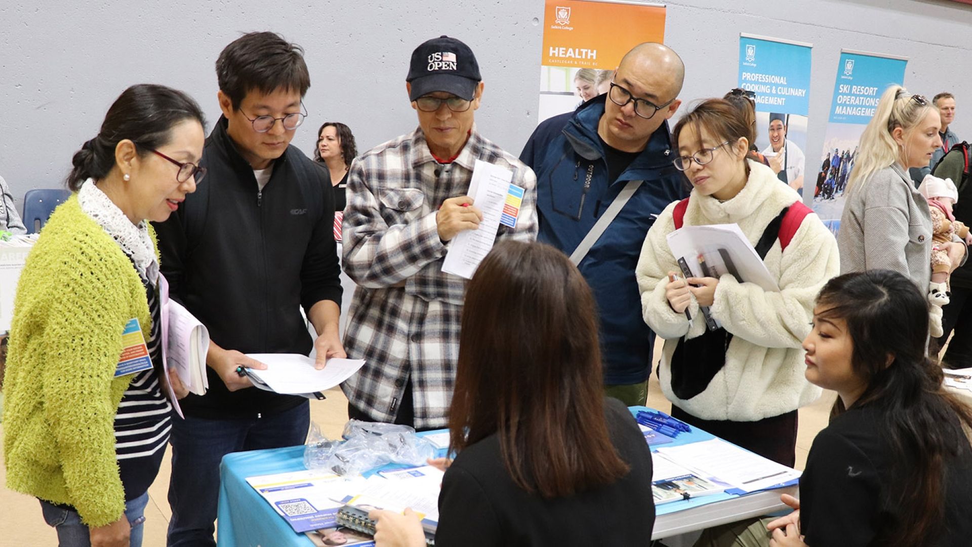 A group of people gather around an information table