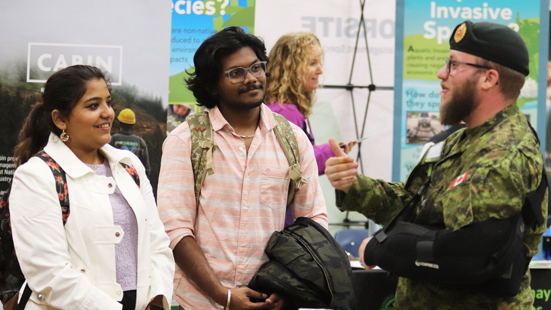 Two students talk to a member of the Canadian military