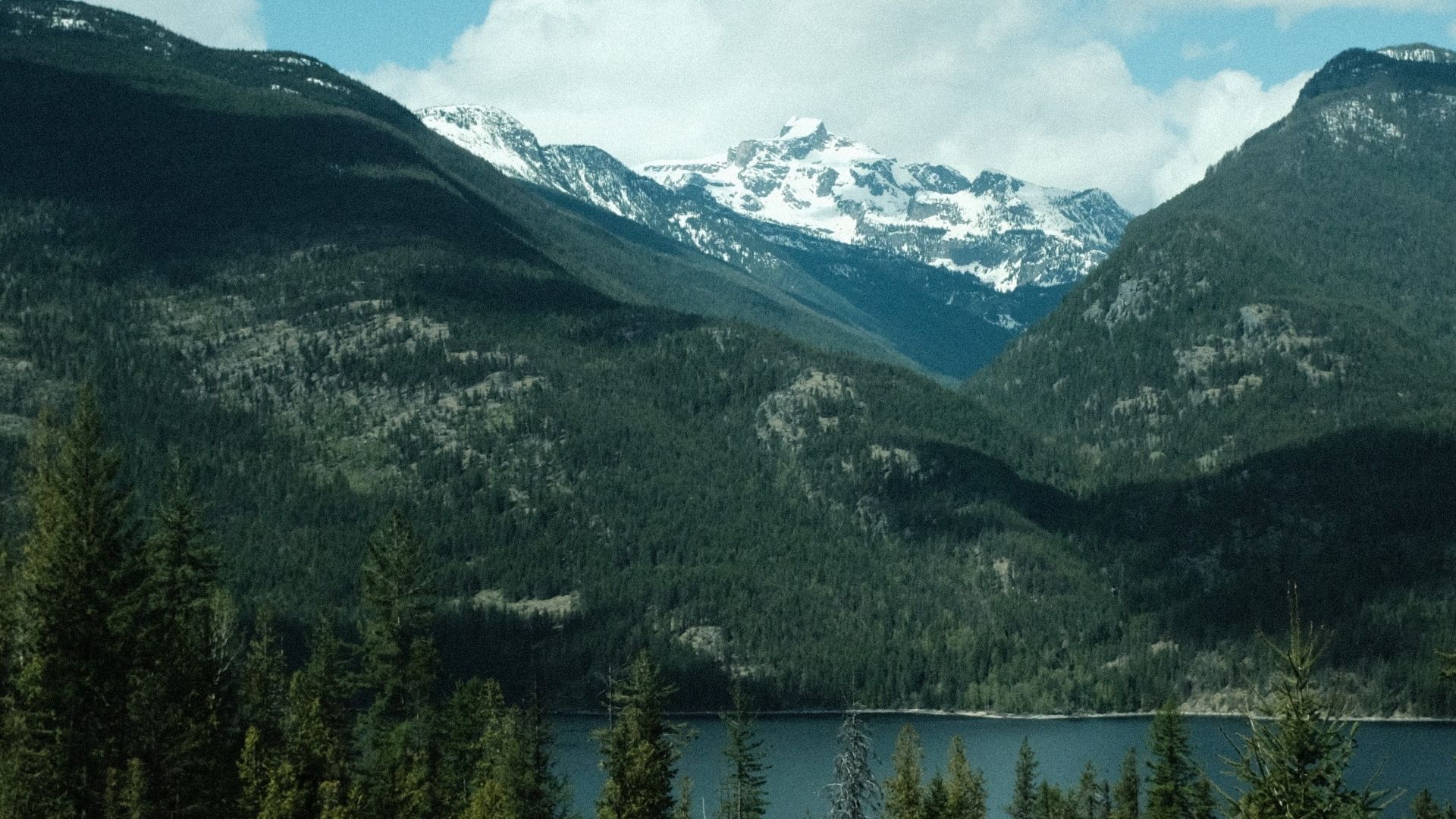 Snow-capped peaks rise above deep green forests