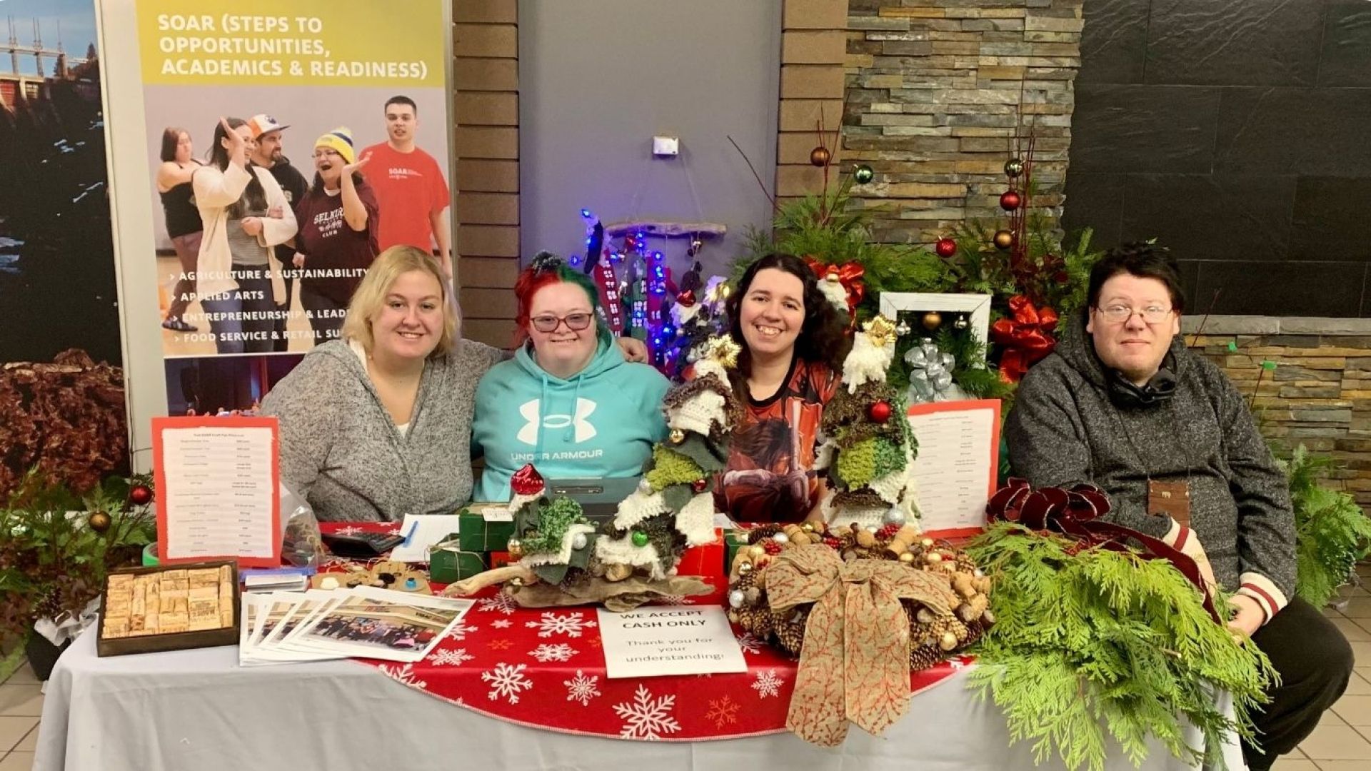 Festive students at craft market table for winter sale