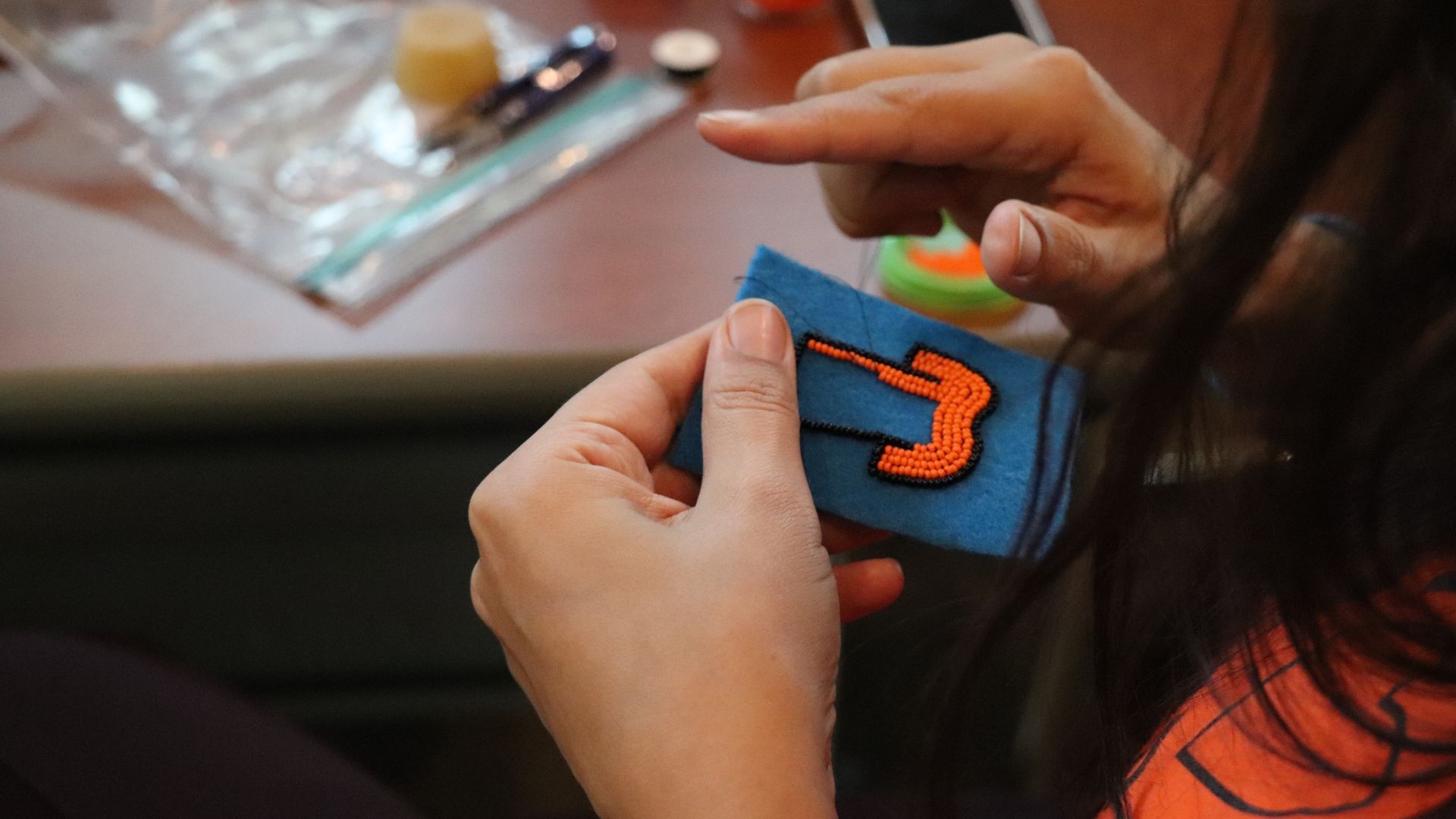 An image of someone beading an orange shirt