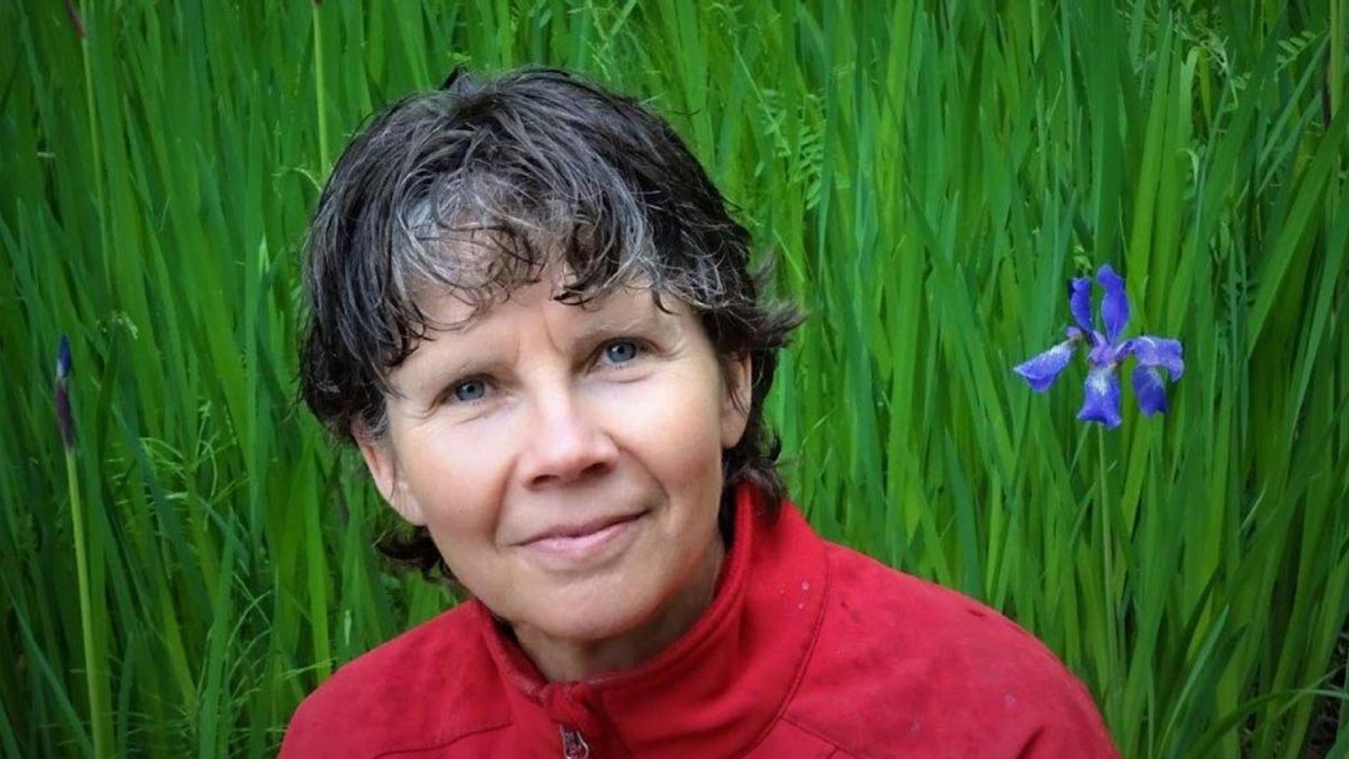 Theresa smiles at the camera against a backdrop of irises