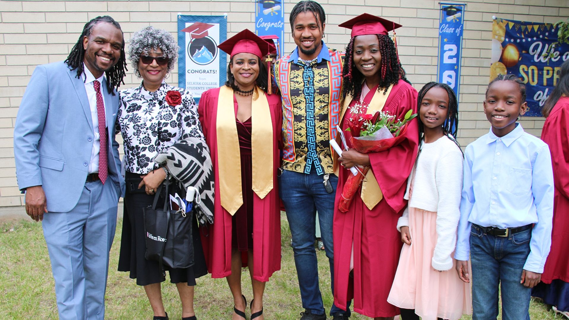 Two families and grads gather on lawn for photo
