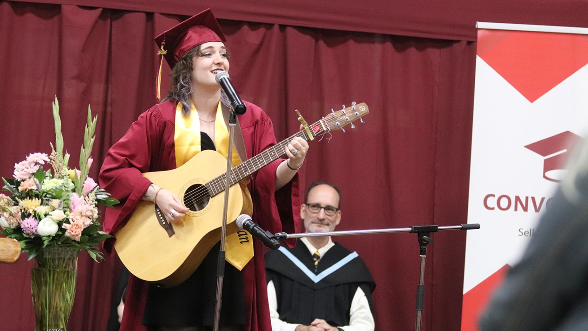 Class of 2024 co-valedictorian Jay Porteous playing guitar on stage
