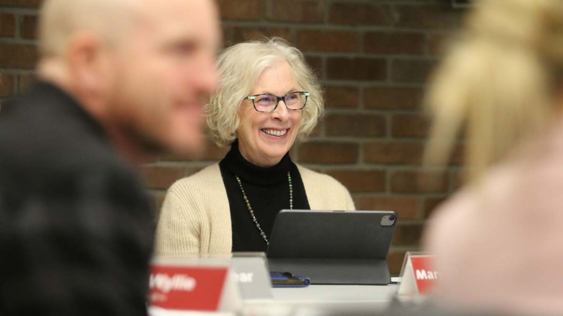 Board Chair Margaret Sutherland sits at a table smiling