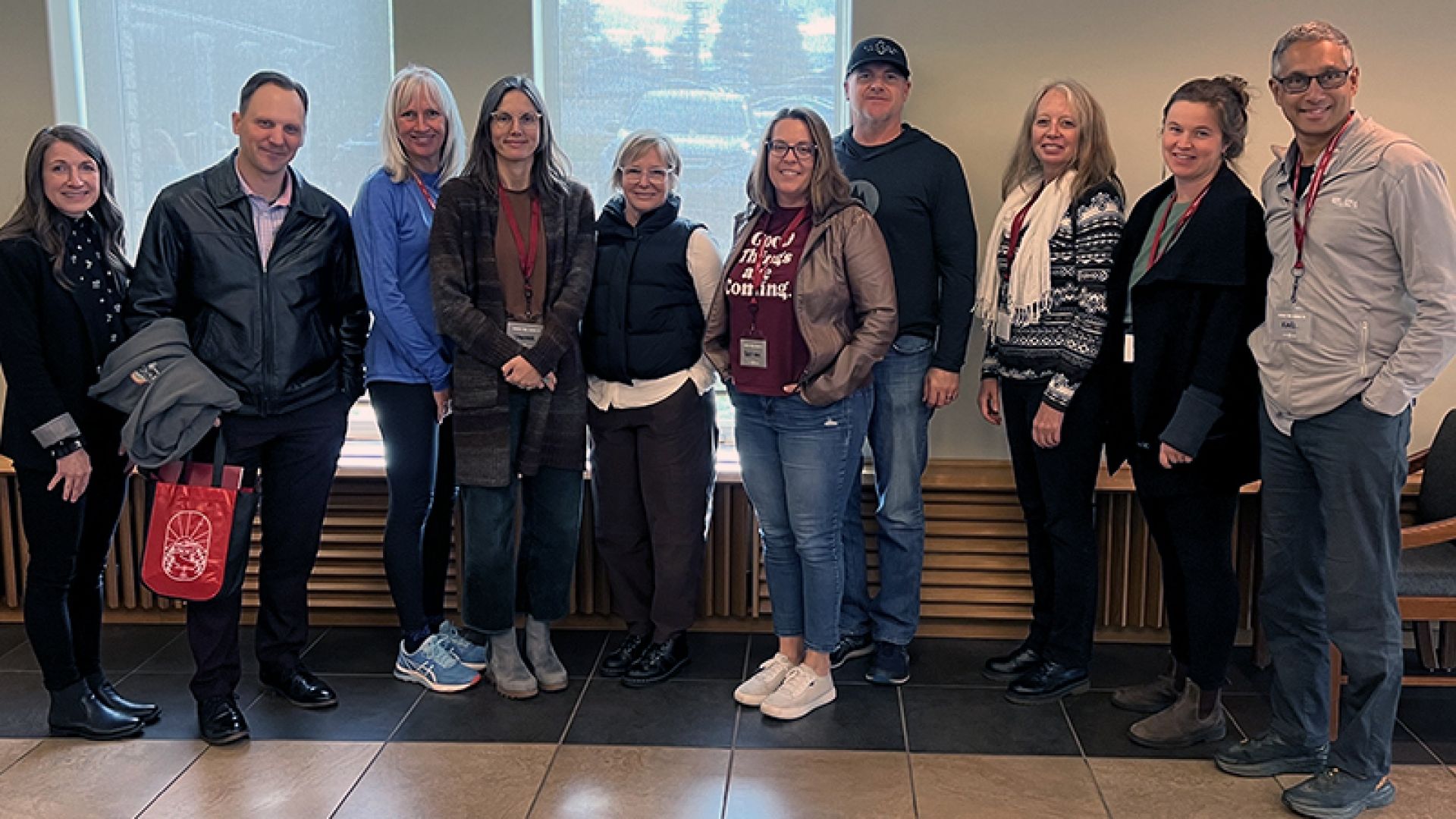 A group of people stand smiling in a hallway