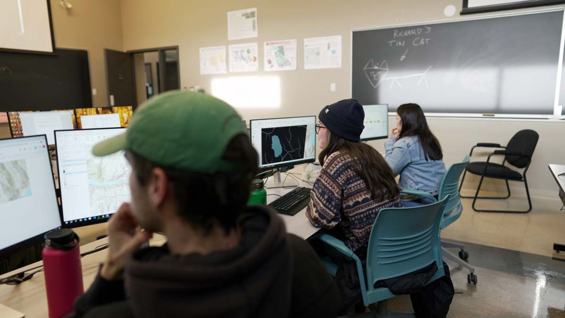Students sit in class and look at graphics on their computer screens