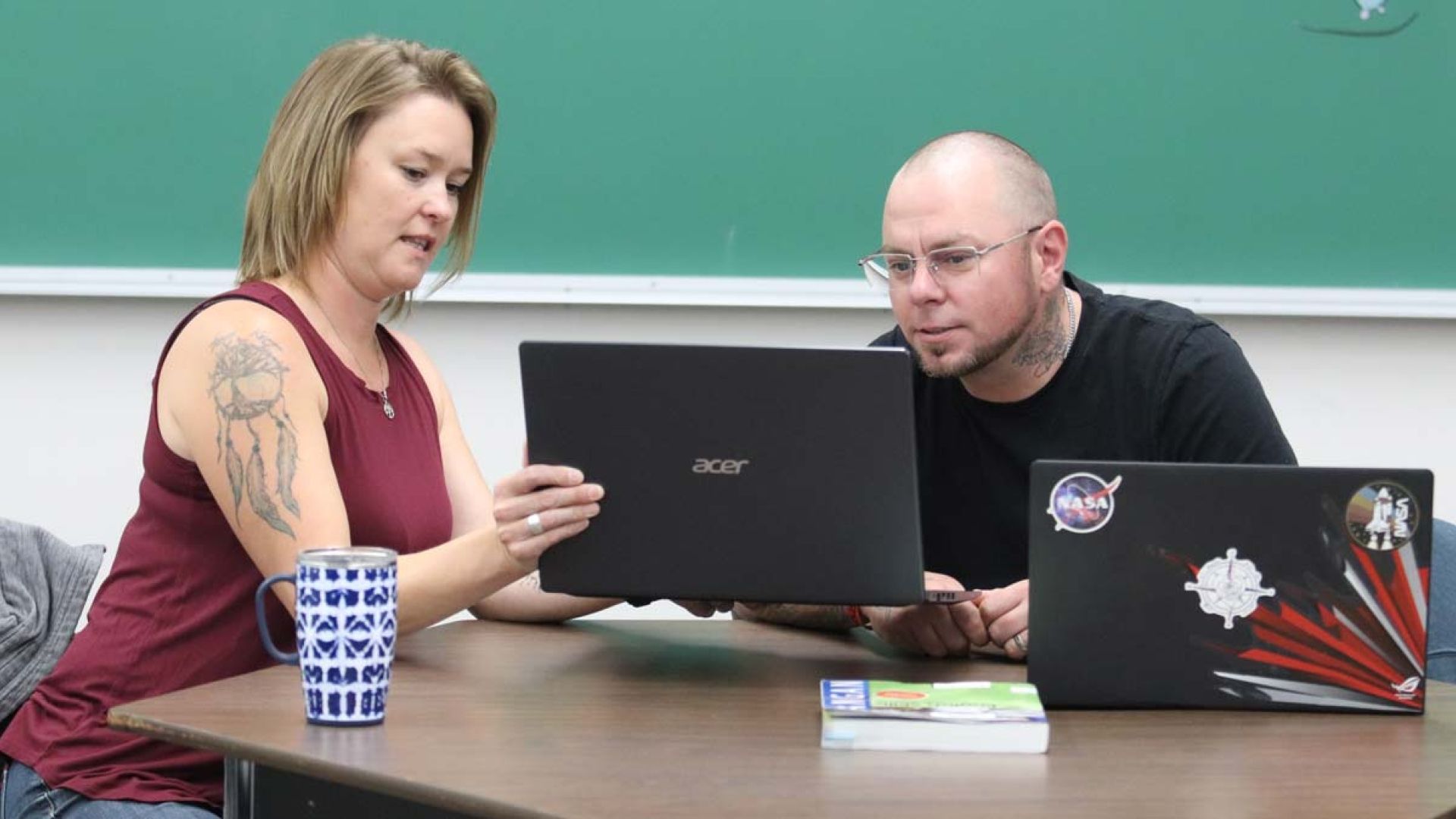 Two people look at a laptop
