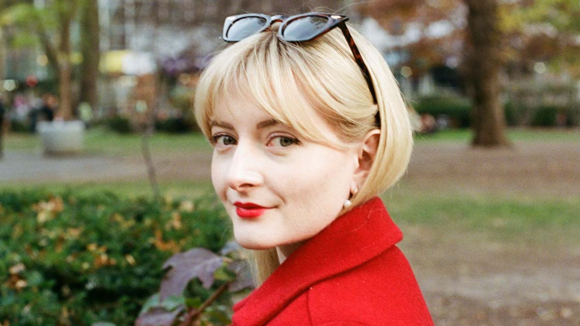 Caity stands in a park and smiles