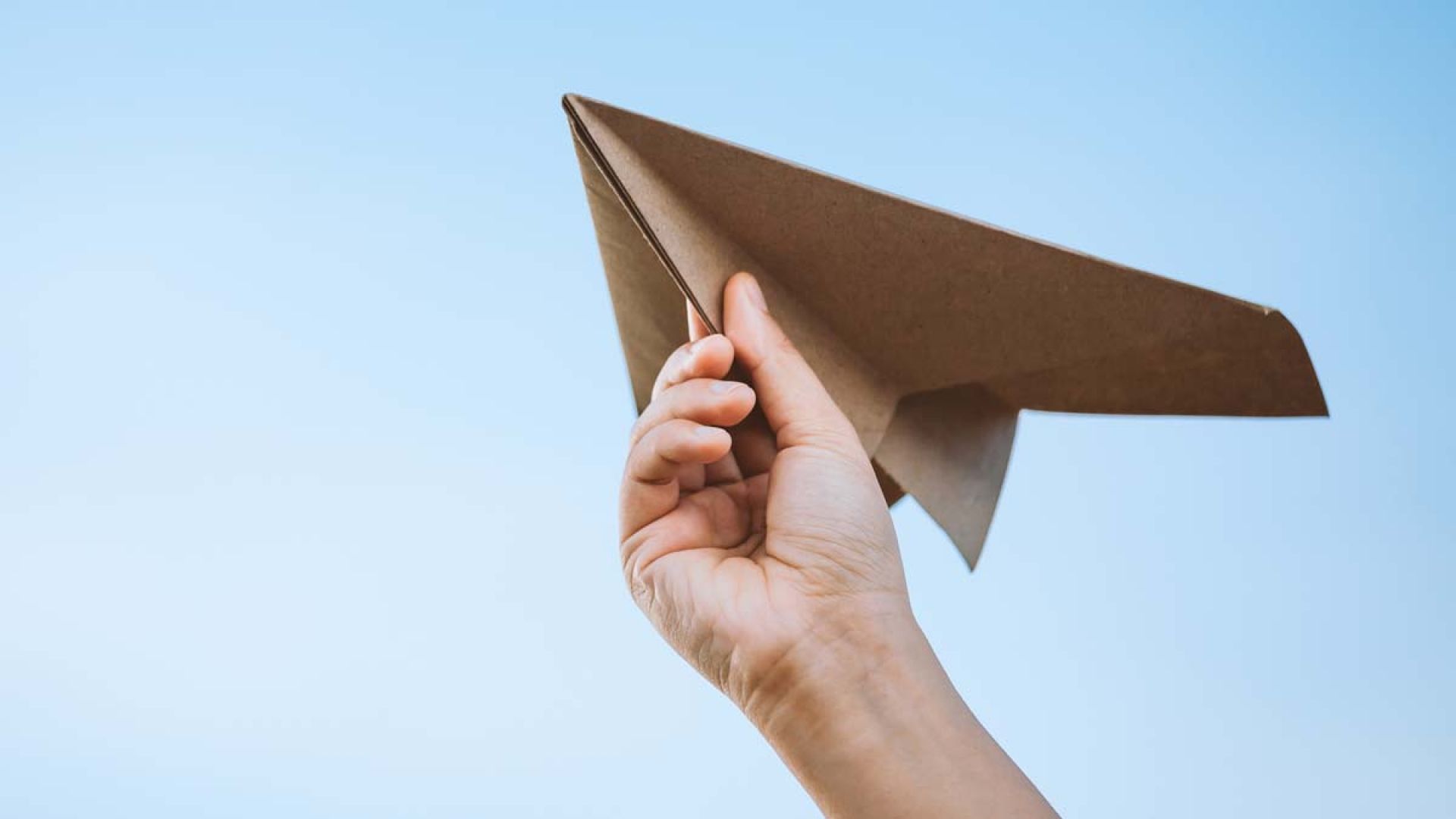 A hand holding a paper airplane