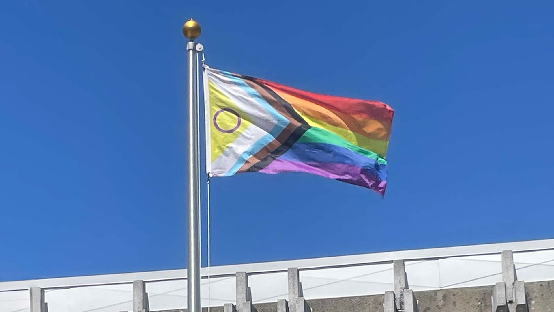 The progressive pride flag flying at the Castlegar Campus