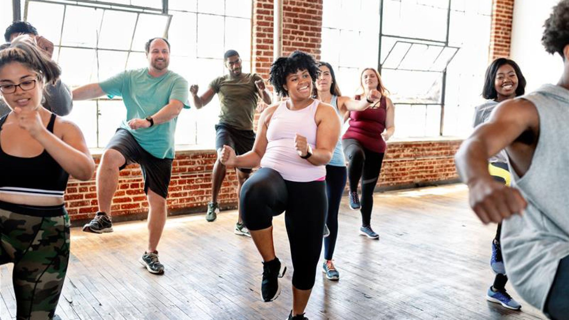 A group of people dance in a Zumba class in a well-lit room