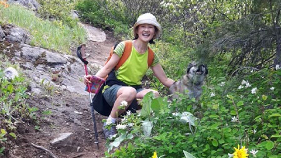 Yoga instructor poses with her dog on a hiking trail