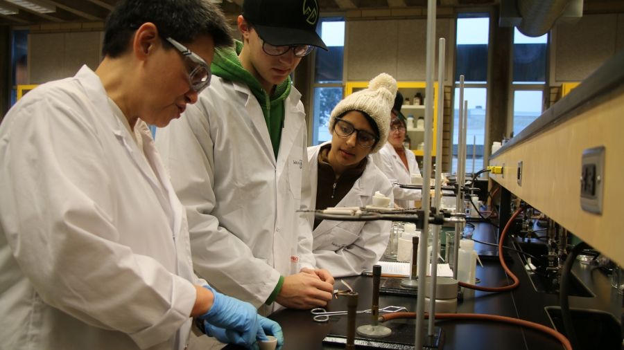 An instructor demonstrates to two students in a lab
