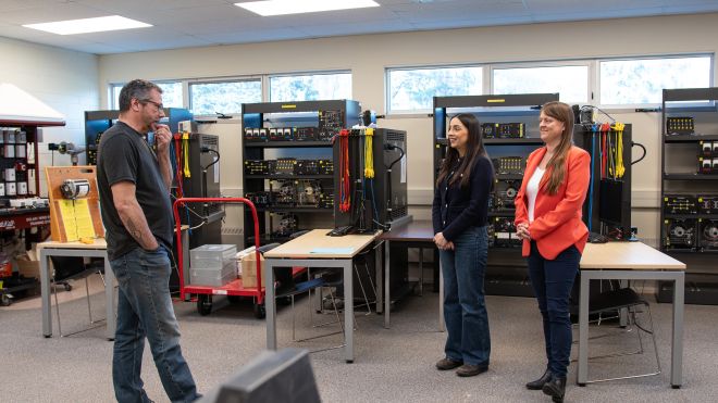 Three people stand in an electrical lab