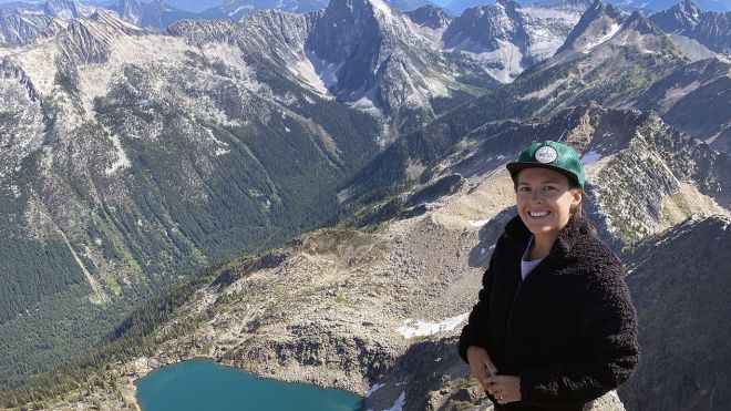 Holli Norberg stands in front of a mountain range
