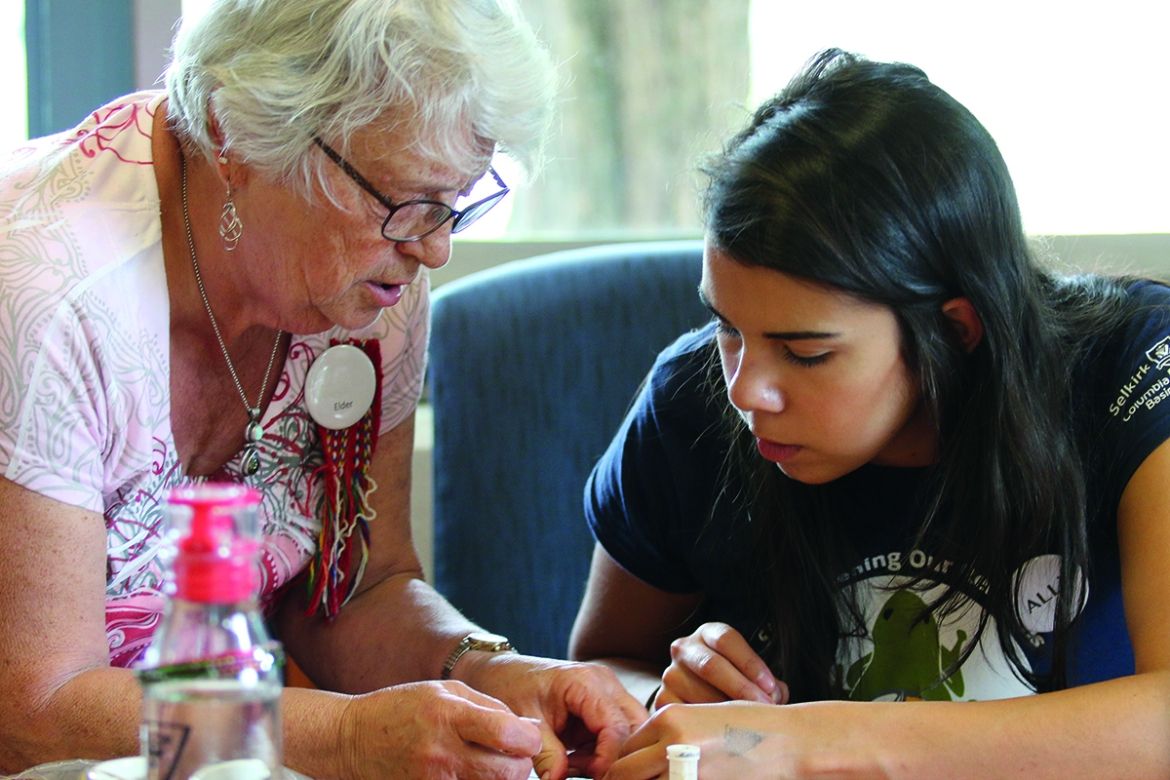 Indigenous Elder helping a youth with a craft