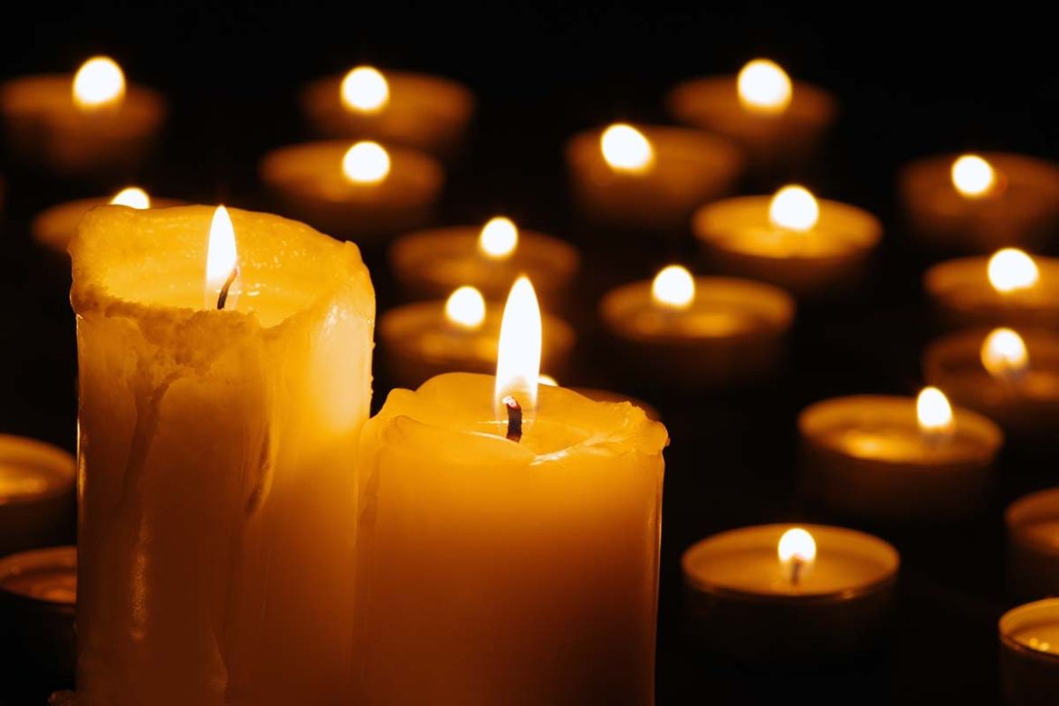Candles burn against a black backdrop