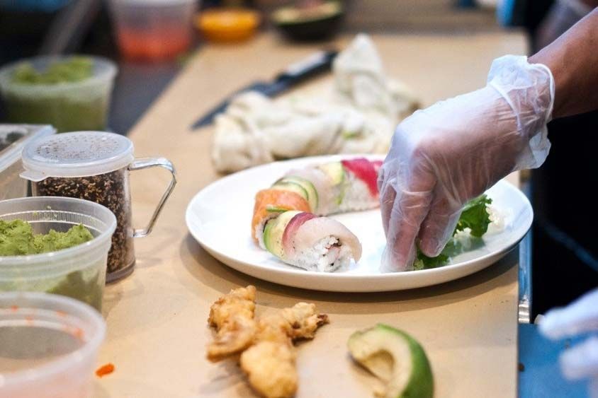 A gloved hand prepares food