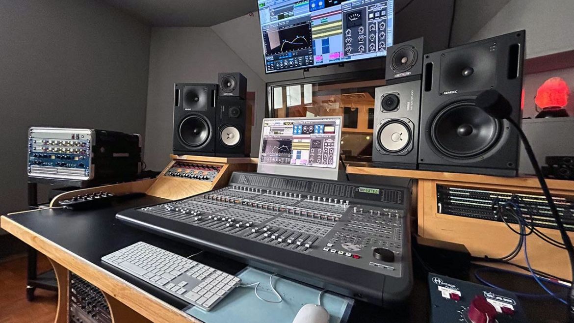 A recording studio with gear, computers and speakers