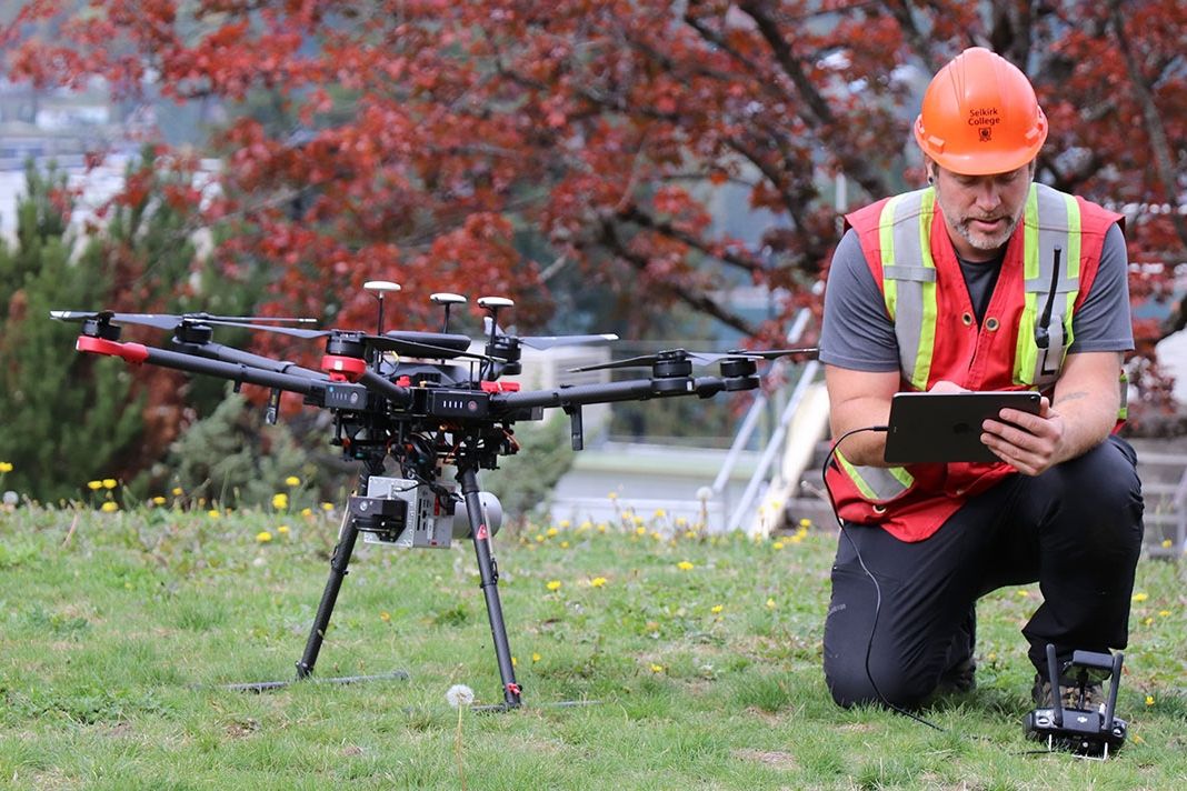 A man kneels next to a drone
