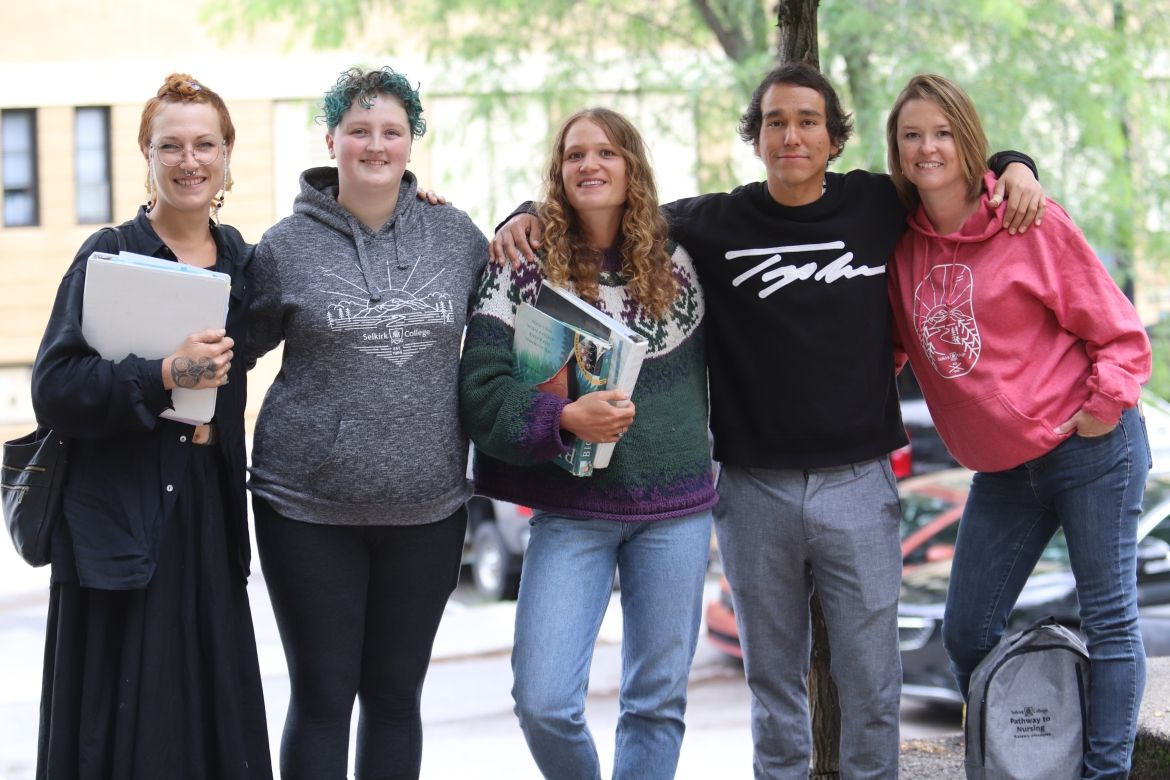Students wearing Selkirk College sweatshirts link arms and smile