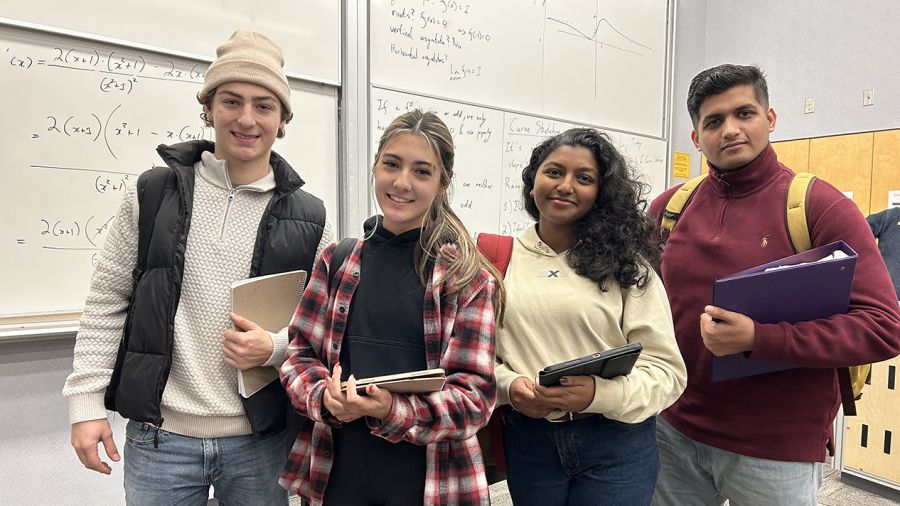 A group of four students stand smiling