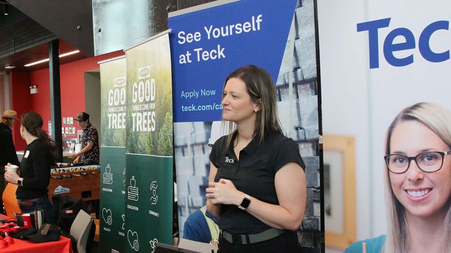A woman stands at a Teck booth at a career fair