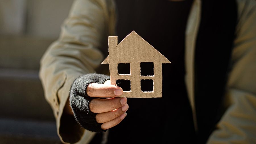 homeless man holding up a cardboard house