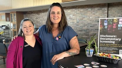 Two people stand smiling