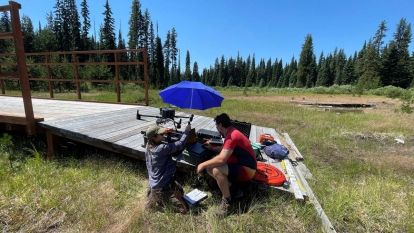 Two people work with a drone in a field