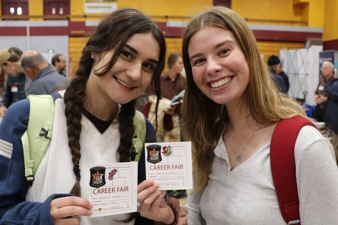 Two smiling people hold up cards reading Career Fair