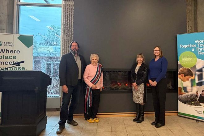 Representatives from Selkirk College and the Columbia Basin Trust stand in front of a new fireplace