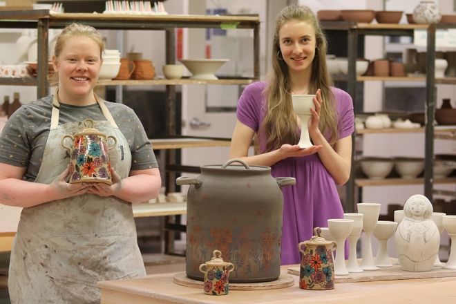 Two Ceramics Program students stand in the shop with their works that are in progress.