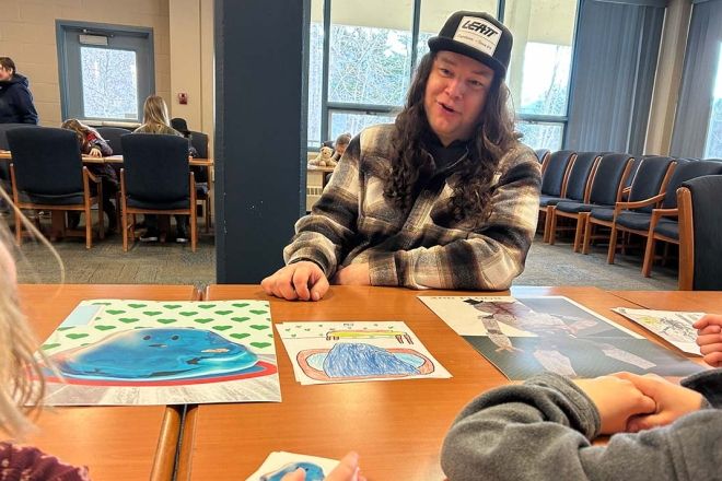 Male Selkirk College student chats with Hume Elementary students at the Monster Party