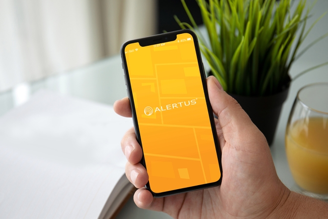 A person holds a phone with the Alertus app open.
