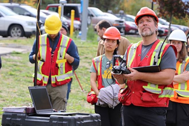 Students and an instructor wearing orange vests fly drones