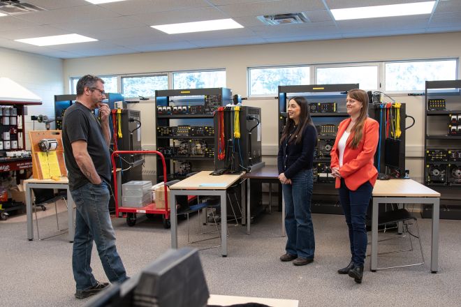 Three people stand in an electrical lab