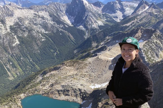 Holli Norberg stands in front of a mountain range