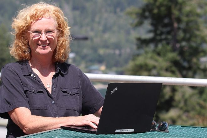 Selkirk College Dean, Allison Alder, sitting at bench with laptop.