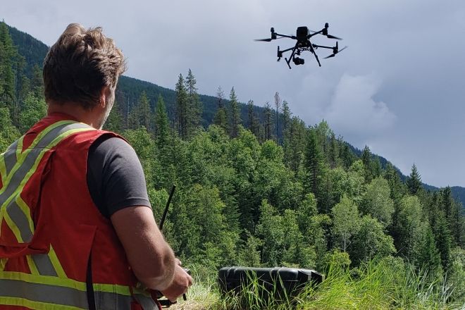 A person in an orange vest flies a drone