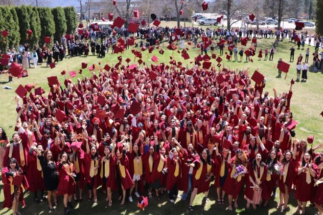 A group of graduates stand together in red robes after Convocation